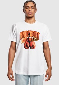 Hvit bomull t-skjorte med grafikk av røde boksehansker og teksten "KNOCKOUT Club" i fet, fargerik skrift.