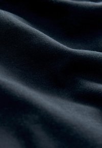 Sötétkék anyag sima textúrával, finom hullámokkal és gyűrődésekkel, bemutatva könnyű és rugalmas tulajdonságait.