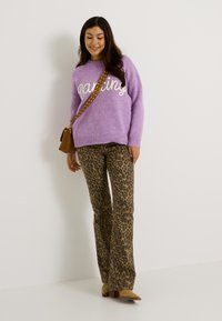 Suéter morado claro con la palabra "Dancing" en texto blanco, combinado con pantalones de campana de estampado de leopardo. Bolso cruzado marrón y zapatos beiges.