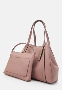 Deux sacs à main en cuir rose de la marque GUESS, l'un plus petit avec une seule poignée et une poche avant, l'autre plus grand avec des poignées doubles et une étiquette de logo.
