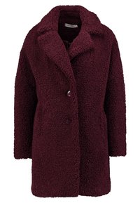 Cappotto teddy texturizzato color bordeaux con colletto a scollo a V, bottoni frontali e tasche laterali, progettato per calore e comfort.
