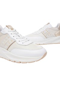 Sneakers bianchi con mesh e pelle sintetica, dotati di borchie dorate sul pannello laterale e accenti beige. Suola spessa per un'altezza aggiuntiva.
