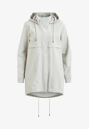 Veste légère gris clair avec capuche et fermeture à boutons-pression à l'avant. Portée sur un t-shirt blanc avec un texte noir audacieux, associée à un jean foncé.