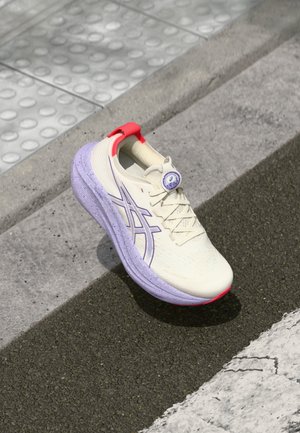 Chaussure de course en crème avec une semelle mouchetée de violet. Comprend un logo violet, un tirant de talon rouge et une tige texturée avec des lacets fins.