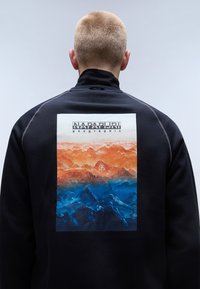 Felpa nera con una grande grafica di paesaggio montano arancione e blu sul retro, con il testo "NAPAPIJRI geographic" sopra.