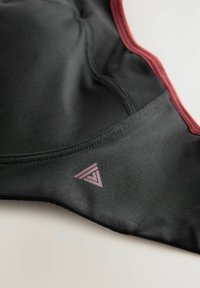 Zwarte sportbeha met kastanjebruine accenten, een gladde textuur en een subtiel driehoekig logo in lichtroze aan de onderkant.