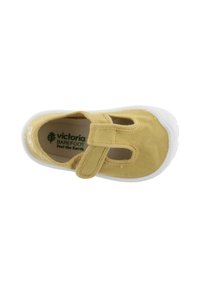 Zapato infantil de lona amarilla con suela de goma blanca, que presenta una tira de Velcro y un diseño recortado, etiquetado como "Victoria Barefoot."