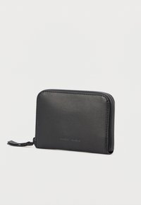 Portefeuille rectangulaire en cuir noir avec fermeture éclair sur tout le tour, avec le nom de la marque discrètement embossé à l'avant, présenté en angle sur un fond clair uni.