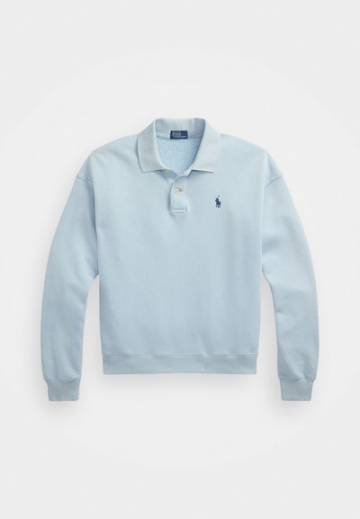 Svetlo modra bombažna polo jopica z dolgimi rokavi, zapenjanjem na dva gumba in majhnim vezenim logotipom v mornarsko modri barvi na prsih. Mehak tekstura.
