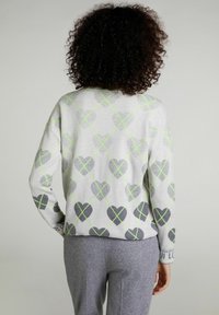 Světlý šedý svetr srdíčkovými vzory v šedé a zelené barvě, s dlouhými rukávy a žebrovaným lemem. Ležérní design s volným střihem.
