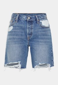 Jeansshorts i ljusblått, med en sliten textur och fransade fållar, samt en klassisk femficksdesign. Knäppning och dragkedja.