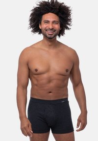 Mustat raidalliset boxerit pehmeästä materiaalista, joka on mukava vyötärö. Mallilla on urheilullinen vartalo ja ystävällinen ilme.