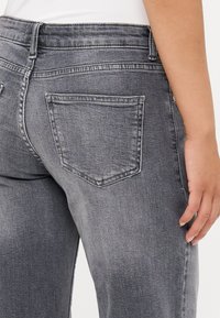 Grå denimjeans med raka ben, bakfickor och en blekt textur. Midjebandet har bälteshyskor för ökat stöd.