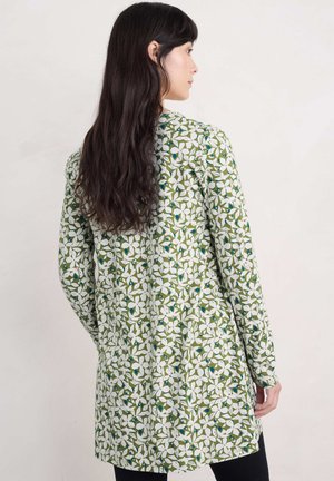 Lange mouwen, groene tuniek met een bloempatroon in het wit en blauw. Zachte stof, rechte snit, tot halverwege de dij, met een ronde halslijn.