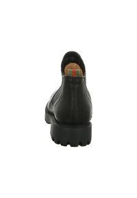 Zapato de cuero negro con una superficie texturizada, tacón bajo y puntera redondeada. Presenta un pequeño acento verde-rojo-verde en la parte trasera.