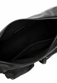 Black leather bag interior, features a zipper closure, soft fabric lining, and side pocket; minimalistic design with no visible hardware.