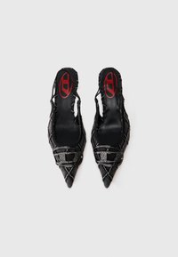 Ζευγάρι μαύρα μπαλαρίνες με μυτερή μύτη και λουράκι πίσω, με υφή καπιτονέ και διακοσμητικές αγκράφες διακοσμημένες με στρας σε λευκό φόντο.