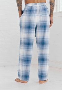 Pantalon de lounge à carreaux avec un motif bleu et blanc, taille élastique, poches latérales et coupe ample, fabriqué en tissu léger.