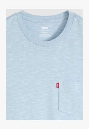 Jasnoniebieska i biała koszulka w cienkie paski z małą kieszonką na lewej piersi oraz czerwoną metką z logo Levi's.