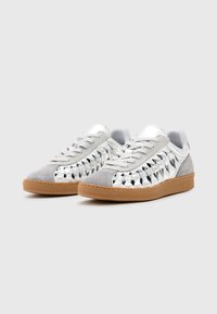 Sneaker con punta in suede grigio e lati in argento metallico con un motivo a piramide, e una suola in gomma marrone per la trazione.