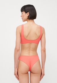 Korálkový bikiny set so priliehavým braletom so širokými ramienkami a zodpovedajúcimi vysokými nohavičkami. Hladká textúra, minimálny dizajn, bez vzorov.
