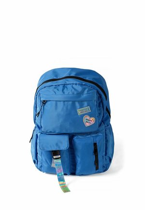 Sac à dos bleu avec plusieurs poches zippées, patchs "Positive Vibes Only" et "Happy Days", et une sangle colorée "Good Vibes" suspendue à l'avant.