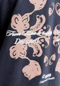 Tissu foncé avec de grands motifs floraux roses et un texte en écriture cursive blanche indiquant "From Vision to reality Designed", avec une marque ©1990 Original Studio.