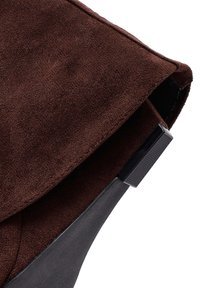 Brown suede boot with a unique fold-over design, featuring a black textured heel for added contrast and stability.