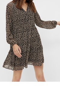 Robe noire à fleurs avec manches longues, col en V et coupe ample. Présente de petits motifs floraux multicolores et un tissu léger texturé.