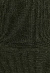 Tissu de pull vert tricoté avec une texture côtelée, présentant des lignes verticales et un aspect doux et légèrement duveteux. Aucun détail matériel visible.