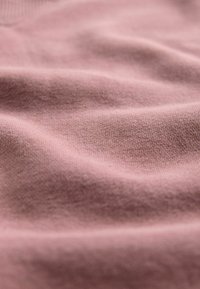 Różny teksturowany materiał z delikatnym drapowaniem. Tkanina wydaje się gładka z drobnym splotem, pokazując subtelne różnice w kolorze i fakturze.