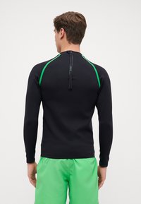 Langärmeliger Rashguard in Schwarz mit grünen Akzenten, ausgestattet mit einem Reißverschluss auf der Rückseite und einer taillierten Passform, die sich für Wasseraktivitäten eignet.