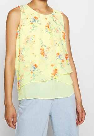 Blusa sin mangas de color amarillo claro con estampado floral en naranja, azul y verde. Tela transparente, diseño en capas y escote redondo.