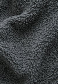 Tessuto in pile grigio scuro con una superficie morbida e testurizzata. Il materiale presenta un motivo arricciato e soffice, che offre calore e comfort.