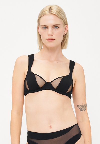 Reggiseno nero con pannelli in rete trasparente, coppe sagomate, spalline larghe e finitura in tessuto liscio. Il design presenta una silhouette scollata.