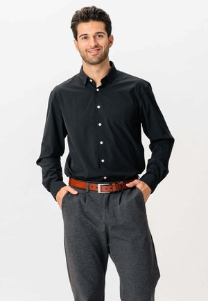 Sort skjorte med knap og krave, lange ærmer; båret med grå bukser og et brunt læderbælte med en sølvbuckle.