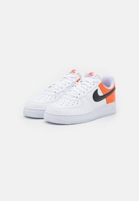 Vita lädersneakers med orange och svarta accenter, perforerad tå, platta snören, texturerad sula och "Nike Air"-logotyp på hälen.
