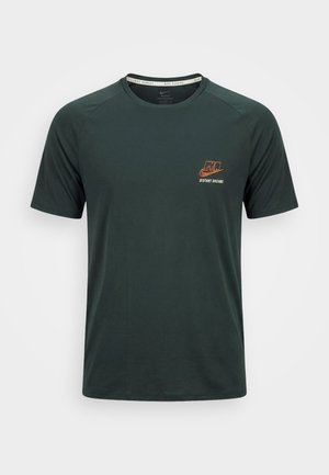T-shirt de course Nike vert foncé à manches courtes, col rond, avec petit logo orange "NIKE DISTANT DREAMS" sur le côté gauche de la poitrine.