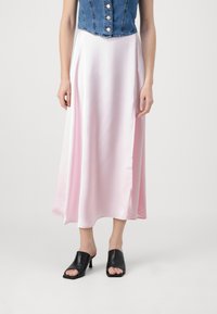 Farmer szövetből készült gombos cropped póló, rózsaszín selyem midi szoknyával párosítva. Fekete nyitott orrú mules cipők. Simító textúra és lebegő design.