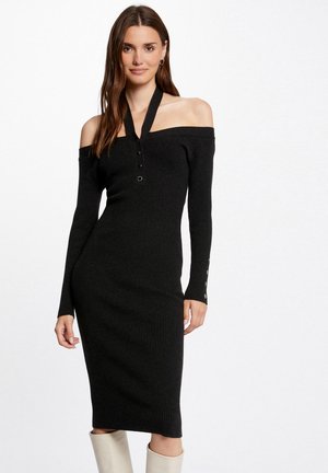 Abito nero a costine con design off-the-shoulder, maniche lunghe, dettagli con bottoni sulla parte frontale e accenti in argento sui bottoni delle maniche.