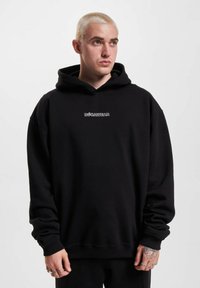 Sort hætte sweatshirt lavet af blødt stof, med et hvidt logo foran. Den har en løs pasform med ribkantede manchetter og kant.