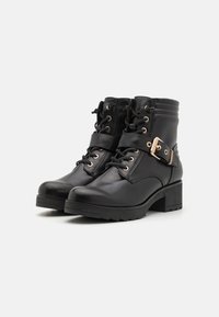 Botas de cuero negras hasta el tobillo con punta redonda, diseño con cordones, correa decorativa con hebilla dorada y suela de goma texturizada.