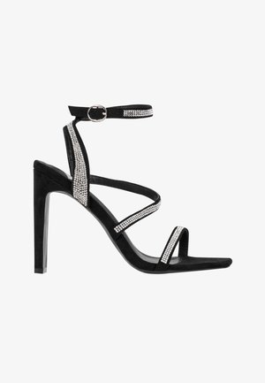 Black suede high-heeled sandal with cross straps and a slim ankle strap. Features rhinestone accents along the straps. Open-toe design.