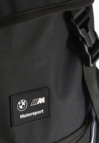 Mustapaha, jossa on teksturoitu kangas. Sisältää kumisen BMW Motorsport -logopatchin ja säädettävät hihnat muoviklipsillä.
