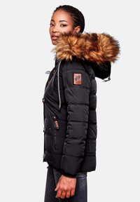 Veste en duvet noire avec capuche en fourrure, présentant une texture matelassée, des poches à fermeture éclair à l'avant et un patch logo sur la manche.