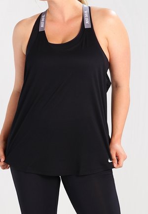 Kobieta ubrana w luźną czarną koszulkę na ramiączkach Nike z napisem "Just Do It." na paskach i czarne legginsy, trzymająca boki koszulki.