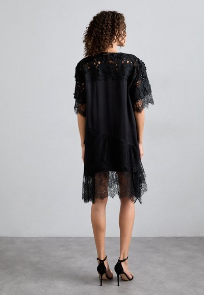 Μαύρο φόρεμα με δαντέλα και λουλουδάτη κεντητή διακόσμηση στα κοντά μανίκια, με διάφανη δαντελένια βάτα και απαλή ύφη. Συνδυασμένο με μαύρες γόβες.
