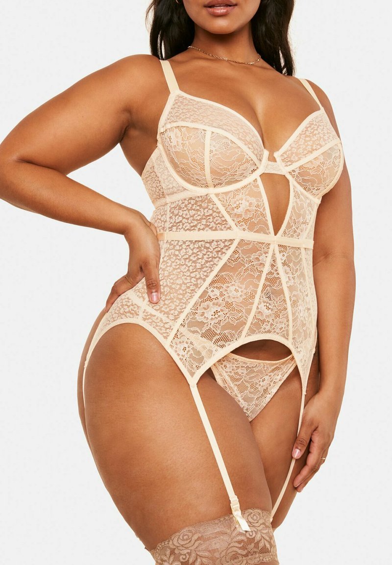 Bodysuit en dentelle beige avec des bretelles réglables, des découpes, des motifs floraux et un design de porte-jarretelles, le tout avec une texture douce.