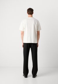 White short-sleeve T-shirt paired with black wide-leg trousers, featuring a smooth fabric texture and a relaxed fit. Plain design, no patterns.