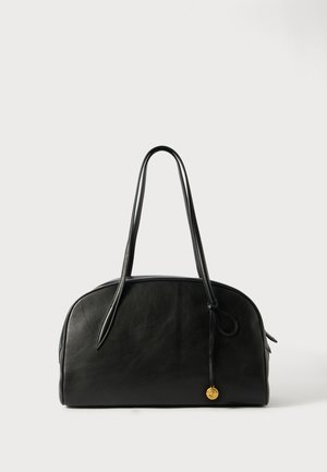 Bolsa de mão em couro preto com uma forma arredondada, duas alças longas e um detalhe em dourado. Textura suave com costura mínima.